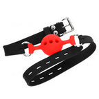 Bâillon boule rouge ajourée en silicone sur longue sangle noire perforée présentée en diagonale, accessoire de soumission BDSM respirant pour imposer le silence.