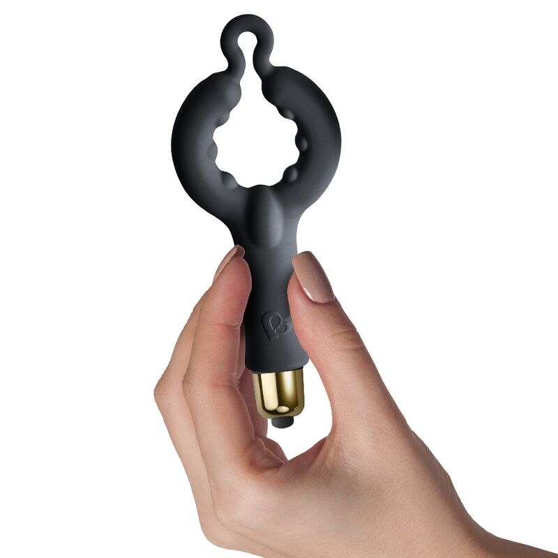 Main féminine tenant l'anneau pénien noir à boucle du pack Silhouette, embout doré visible, illustrant le petit gabarit de l'accessoire en silicone lisse non anatomique.