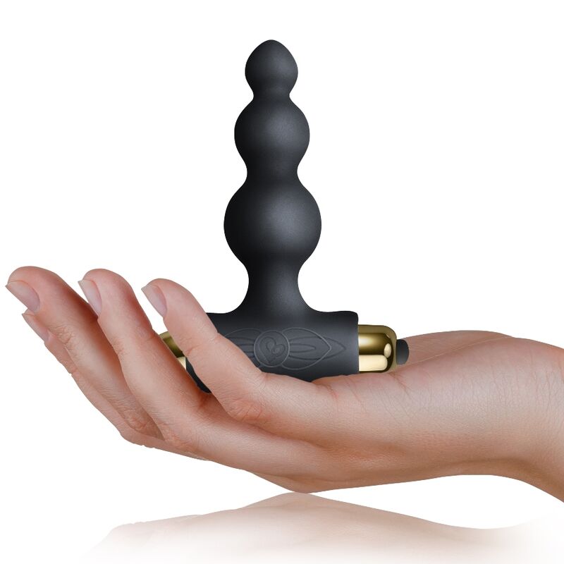Plug perlé noir posé sur la paume d'une main, billes étagées et base en T visibles, montrant le petit format de l'accessoire anal en silicone du pack Silhouette.