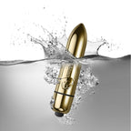 Balle vibrante dorée du pack Silhouette plongeant dans l'eau avec éclaboussures, illustrant l'étanchéité du mini vibro, surface métallisée lisse non anatomique.