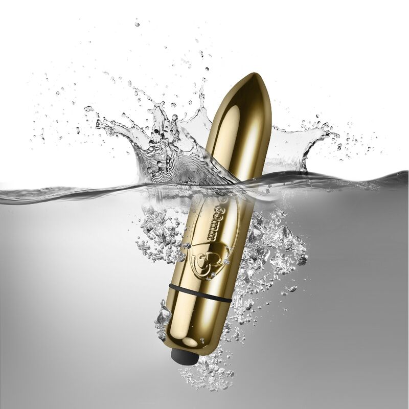 Balle vibrante dorée du pack Silhouette plongeant dans l'eau avec éclaboussures, illustrant l'étanchéité du mini vibro, surface métallisée lisse non anatomique.