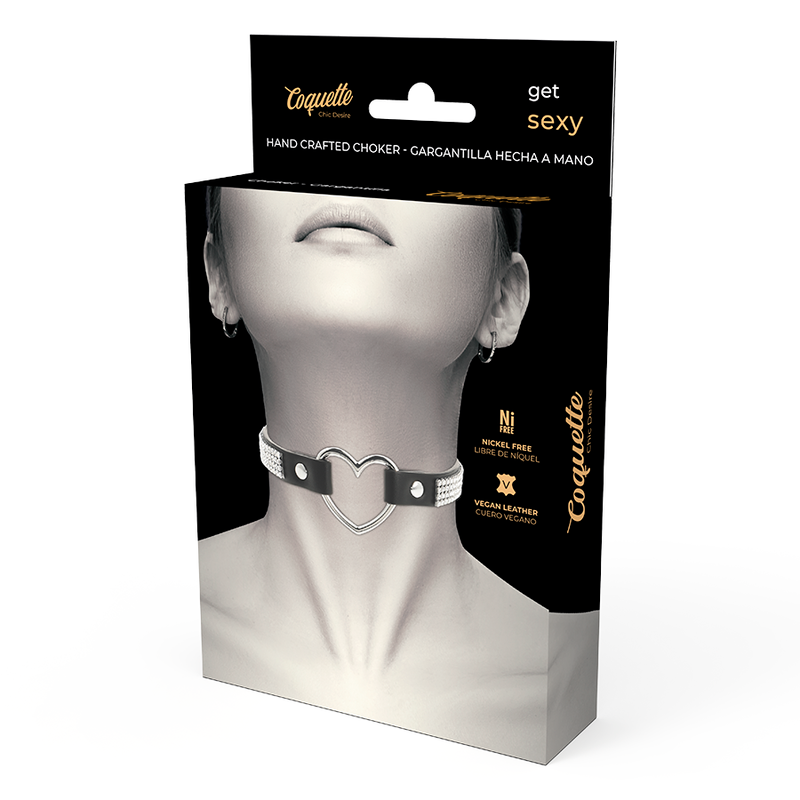 Ras de cou cuir vegan Coquette a anneau metal en cœur presente devant sa boite produit, accessoire fetiche serti de strass pour sublimer une tenue audacieuse.