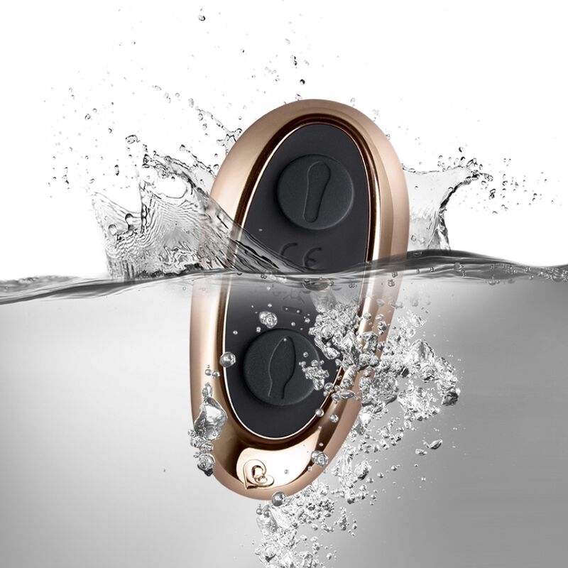 Télécommande dorée ovale du Cocktail plongeant dans l'eau avec éclaboussures, deux molettes visibles, démontrant l'étanchéité de l'accessoire de commande.