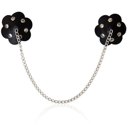 Paire de cache-tetons boucliers en forme de petale noir cloutes, relies par une fine chaine metallique, accessoire fetichiste reutilisable et sans nickel pour habiller la poitrine.