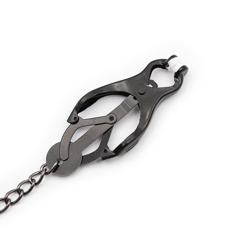 Gros plan sur une seule pince a tetons clover noire a embout caoutchoute, reliee a un debut de chaine, montrant la machoire articulee qui adapte la pression au teton.