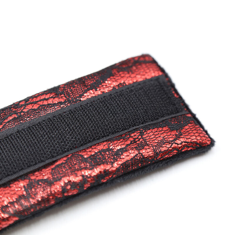 Gros plan sur la sangle velcro d'une manchette en velours noir doublee de dentelle rouge, systeme de fermeture reglable d'une attache de poignet douce pour la peau.