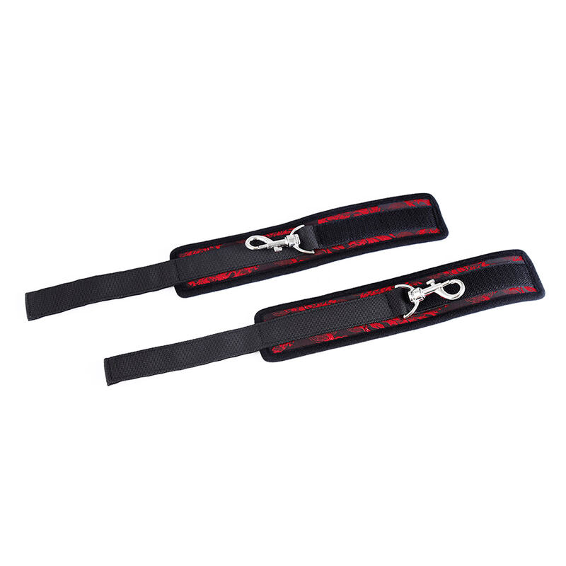 Paire de menottes neoprene noir et rouge en gros plan, bracelets reglables relies par un mousqueton metallique, kit d'attaches confortable pour initiation BDSM.