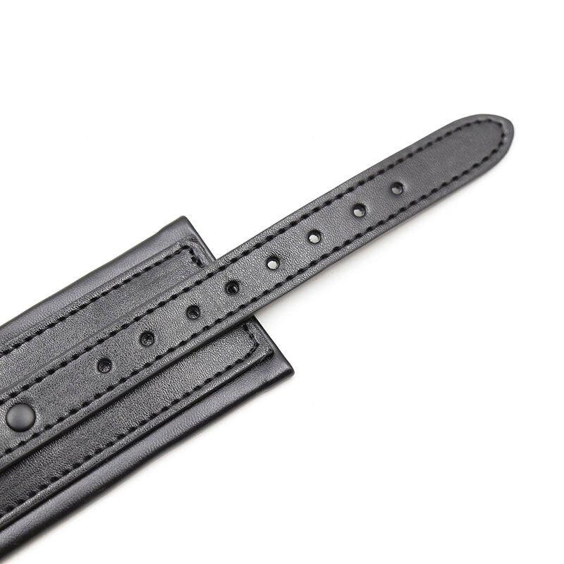 Gros plan sur une sangle simili cuir noir matelassee percee d'oeillets de reglage, detail des manchettes d'attache rembourrees Ohmama pour le bondage.