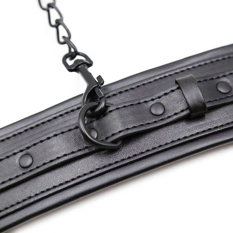 Detail de la chaine noire reliant deux manchettes en simili cuir noir a rivets, fixation des menottes de contention aux finitions sombres Ohmama.
