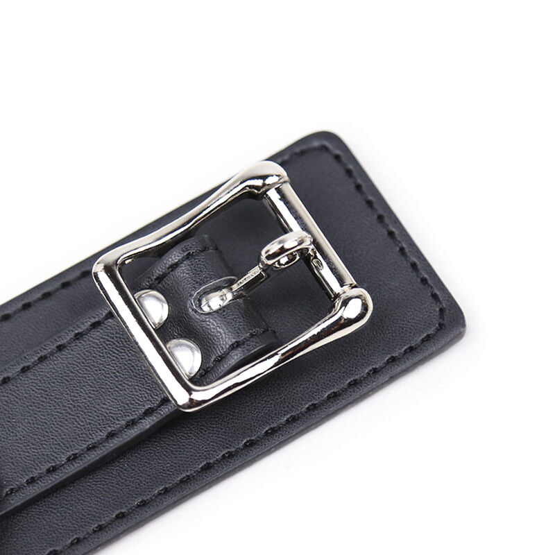 Gros plan sur la large boucle metallique et les surpiqures d'un collier en simili cuir noir, detail de la fermeture du collier de soumission Ohmama.