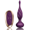 Plug anal vibrant en silicone violet torsadé à pointe effilée, col fin et base bulbeuse, posé près de la télécommande ovale dorée, surfaces lisses non anatomiques.