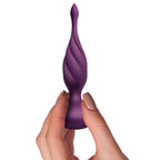 Main féminine tenant le plug anal violet torsadé à pointe effilée par sa base bulbeuse, illustrant la forme fine et progressive du jouet anal en silicone violet.
