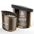 Bougie de massage Senze Euphoria vanille bois de santal, verre brun fume allume devant sa boite, cire chaude nourrissante qui se transforme en huile.