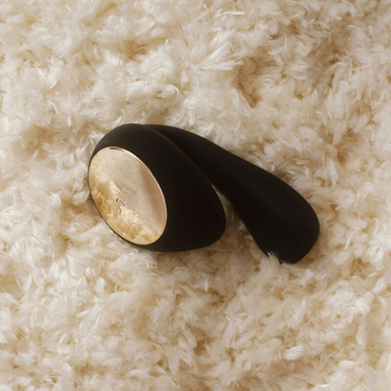 Gros plan du stimulateur de couple IDA Wave de Lelo en silicone noir aux reflets dorés, posé sur une fourrure beige douce, vue rapprochée de sa courbe.