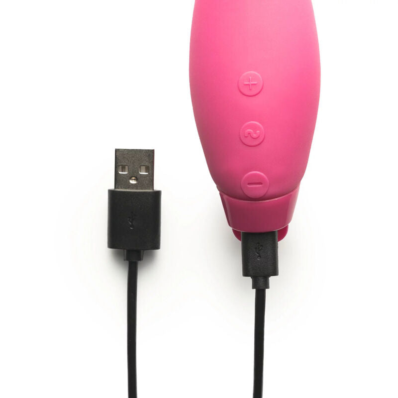 Manche du vibromasseur Juno rose avec ses trois boutons plus, central et moins, relié au câble de charge USB noir branché, détail de l'interface et de la recharge sur fond blanc épuré.