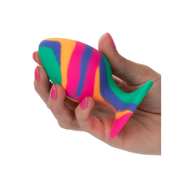 Plug anal Cheeky Large en silicone tie-dye multicolore tenu en main, mise à l'échelle du corps souple bombé et de la base ventouse de ce plug grande taille.