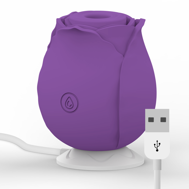 Stimulateur clitoridien violet en forme de rose pose sur son socle de charge avec cable USB, silicone rechargeable, format compact et discret.