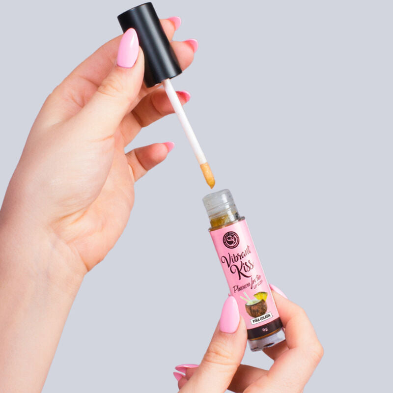 Flacon gloss Vibrant Kiss Secretplay pina colada tenu en main, applicateur deploye, gloss a levres vibrant comestible diffusant un picotement doux.