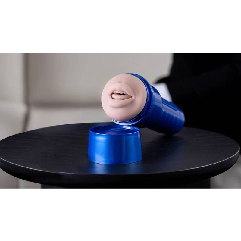 Masturbateur bouche Fleshlight Boost pose en angle sur une table, orifice oral moule realiste visible et boitier bleu metallise de la gamme a aspiration.