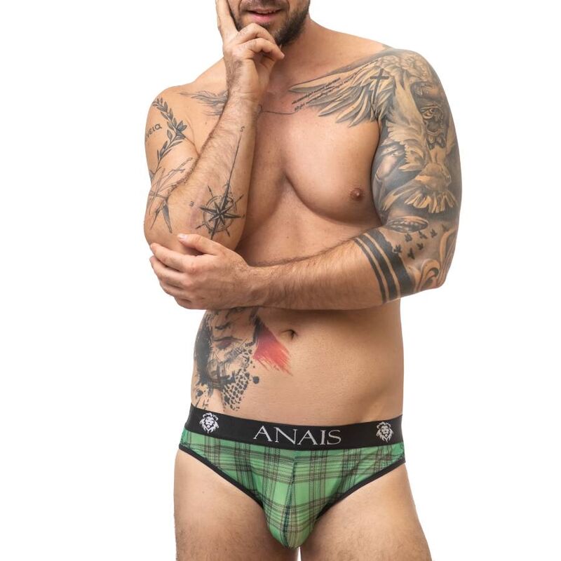 Homme torse nu tatoue portant le slip Magic en lycra a carreaux verts et noirs, ceinture Anais, gros plan trois-quarts sur la lingerie masculine moulante.