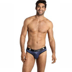 Homme souriant torse nu de face en slip Naval a rayures satinees bleu marine, ceinture Anais, tulle moulant la silhouette, lingerie masculine raffinee.