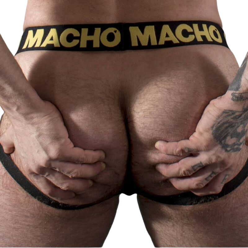 Jockstrap homme noir effet cuir vu de face en gros plan, ceinture logo Macho doree et pochette galbante en similicuir extensible brillant et sensuel.