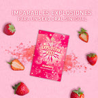 Sachet de bonbons explosifs Explosive Kiss saveur fraise sur fond rose, entoure de fraises fraiches. Bonbons comestibles petillants pour pimenter le sexe oral en couple.