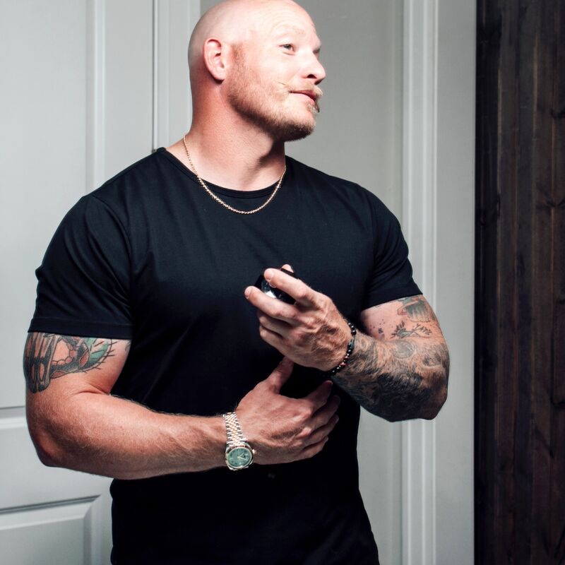 Homme muscle en t-shirt noir consultant son telephone, mise en scene masculine de la gamme parfum aux phéromones Matchmaker Black Diamond Eye Of Love, sans nudite.