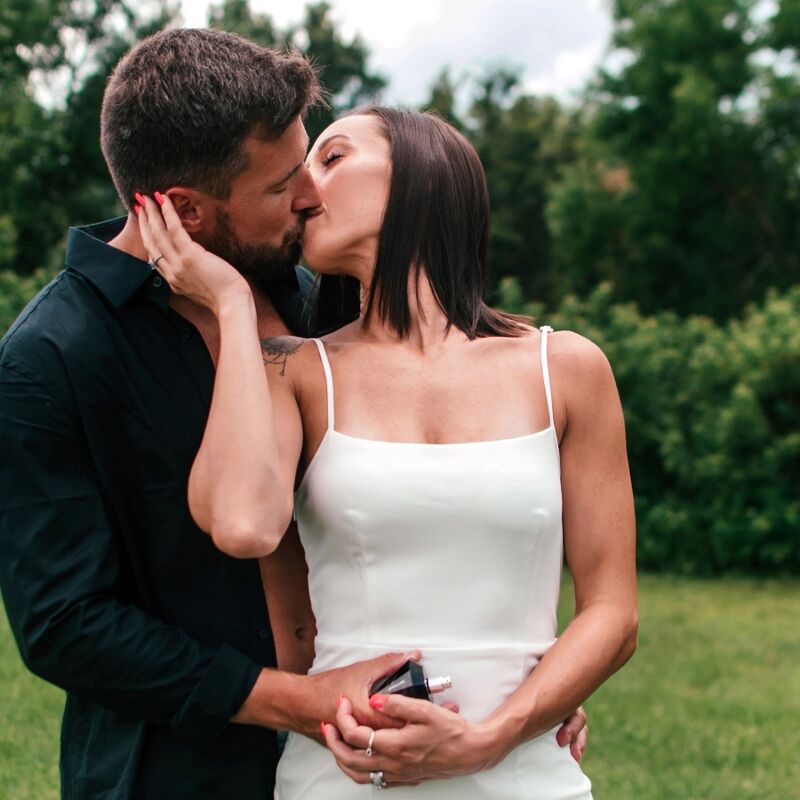Couple habille s'embrassant en exterieur, lui en chemise sombre elle en robe blanche, mise en scene romantique de la gamme parfum aux phéromones Matchmaker Eye Of Love.