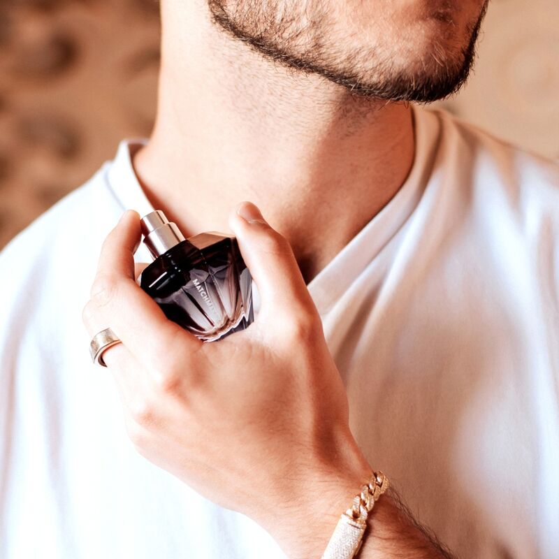 Homme en t-shirt blanc tenant le flacon diamant noir du parfum phéromones Matchmaker Black Diamond contre son cou, eau de parfum facette en main, scene lifestyle Eye Of Love.