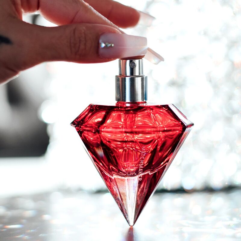 Main vaporisant le flacon diamant rouge du parfum aux phéromones Matchmaker Red Diamond, eau de parfum facette a bouchon cristal en gros plan, fragrance jasmin ambre.