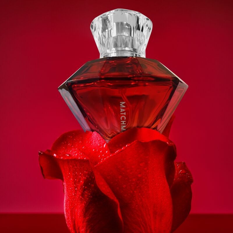 Flacon diamant rouge du parfum aux phéromones Matchmaker Red Diamond pose sur une rose, eau de parfum facette a bouchon cristal, fragrance sensuelle jasmin ambre Eye Of Love.