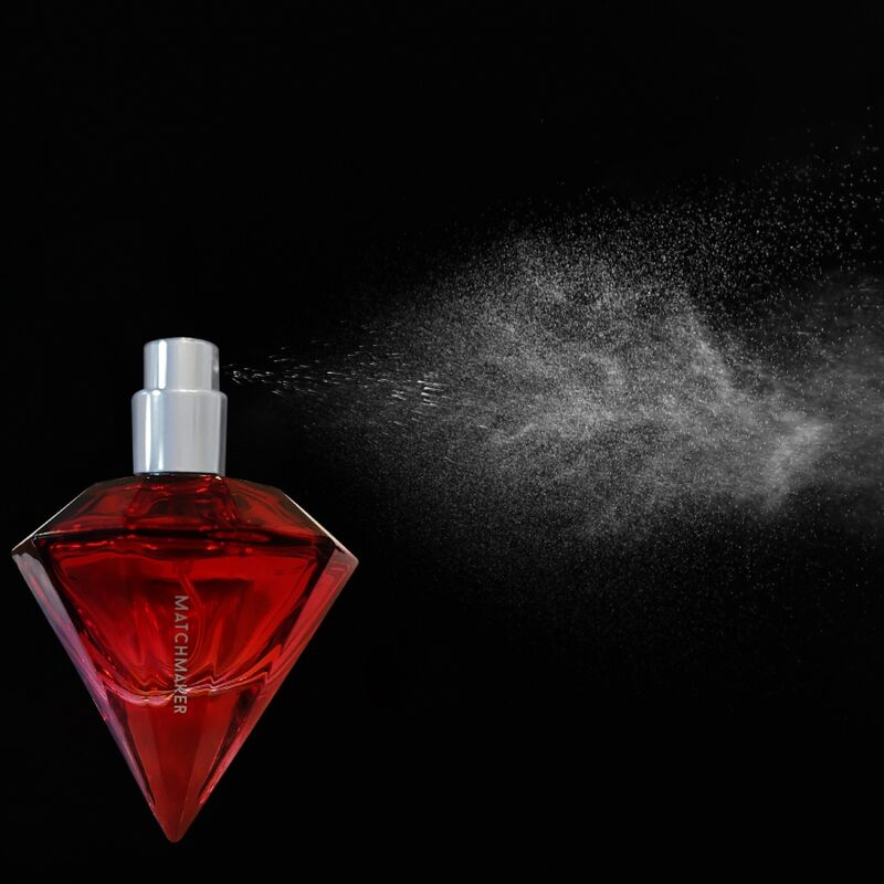 Flacon diamant rouge du parfum aux phéromones Matchmaker Red Diamond vaporise sur fond noir, nuage de brume visible, eau de parfum facette a bouchon cristal Eye Of Love.