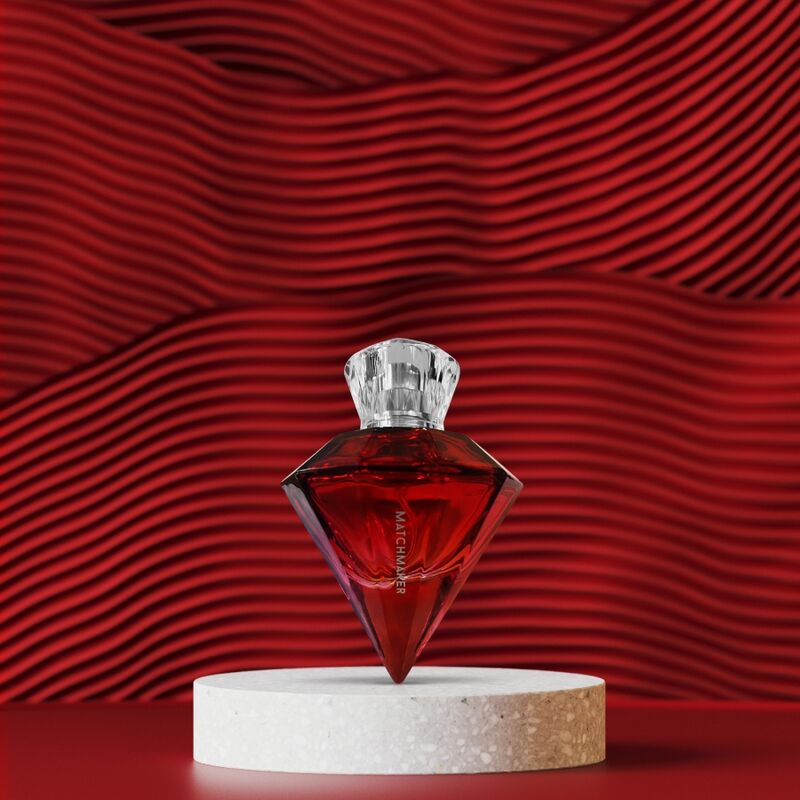 Flacon diamant rouge du parfum aux phéromones Matchmaker Red Diamond pose sur un socle, fond rouge ondule, eau de parfum a bouchon cristal jasmin pamplemousse ambre Eye Of Love.