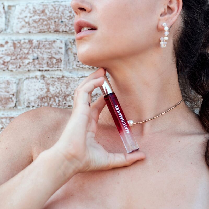 Femme epaules denudees appliquant le roll-on Matchmaker Red Diamond sur le cou, mise en situation du parfum aux pheromones unisexe 10 ml Eye Of Love.
