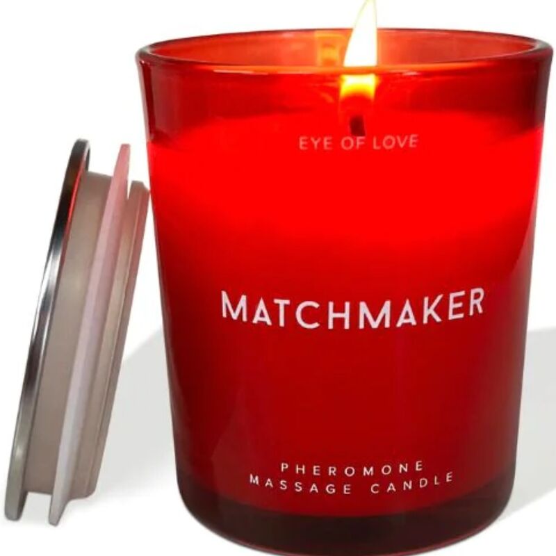 Bougie de massage rouge Matchmaker allumee avec son couvercle metal pose a cote, soin aux pheromones 150 ml beurre de karite Eye Of Love.