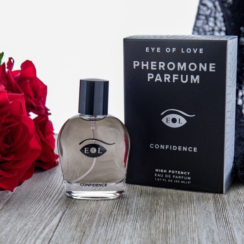 Flacon Confidence et sa boite mis en scene avec des roses rouges, eau de cologne aux pheromones pour homme 50 ml notes musquees Eye Of Love.
