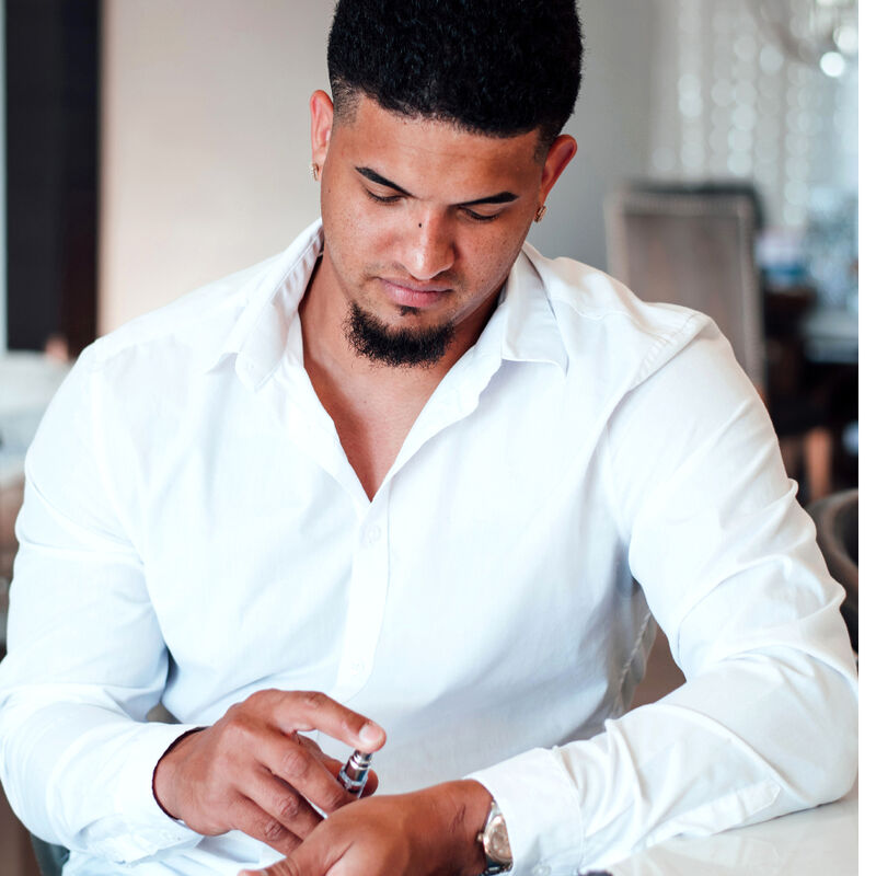 Homme en chemise blanche tenant le roll-on Romantic, mise en situation du parfum aux pheromones Romantic pour homme 10 ml notes boisees Eye Of Love.