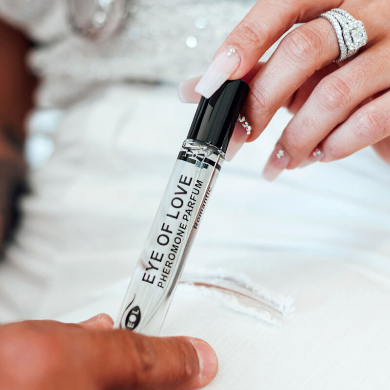 Main baguee tenant le roll-on Romantic, gros plan sur le parfum aux pheromones Romantic pour homme 10 ml format voyage Eye Of Love.
