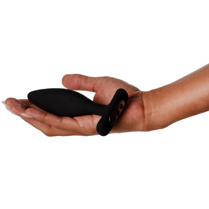 Plug Vesta noir posé en travers d'une paume ouverte aux ongles soignés, base à anneau bien visible, plan illustrant les dimensions compactes du plug en silicone sur fond blanc.