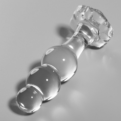 Gros plan en biais du plug anal en verre borosilicate transparent perle, surface lisse et reflets, base large securisee, matiere non poreuse compatible chaud et froid.