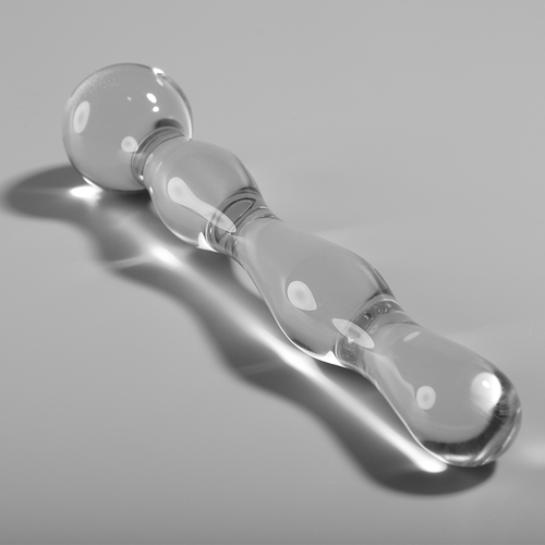 Gode double en verre borosilicate transparent Nebula Series couche sur fond gris, sphere lisse et renflements ronds, tige droite, matiere non poreuse thermique.