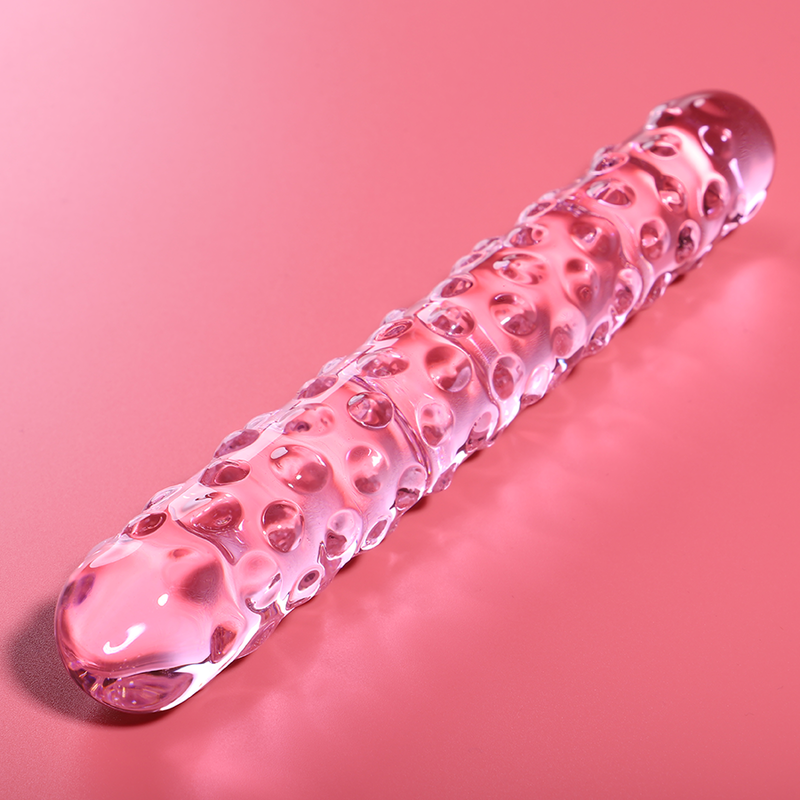 Double gode en verre borosilicate rose Nebula Series couche sur fond corail, longue tige texturee de picots en relief et embouts arrondis, surface non poreuse hygienique.