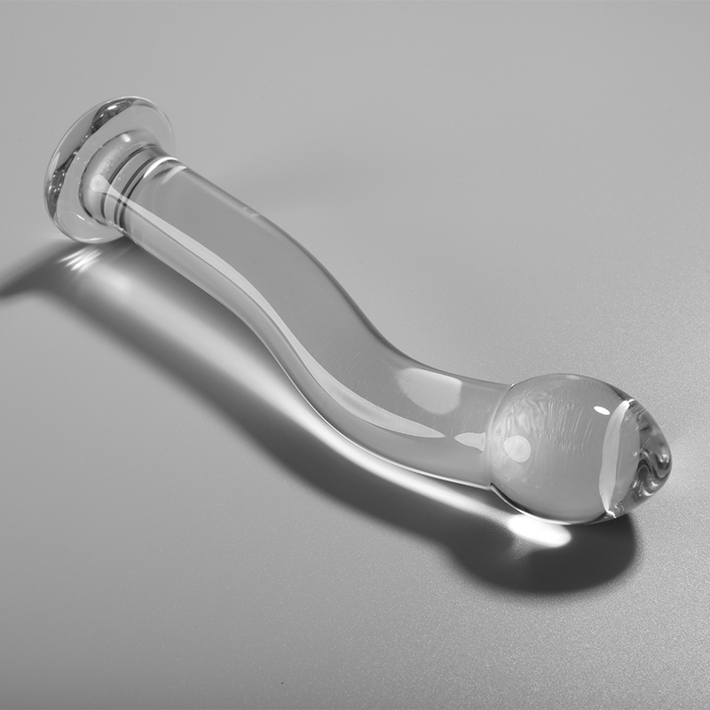 Gode en verre borosilicate transparent couche sur fond gris, forme courbee avec embout bulbe et base spherique lisse, matiere non poreuse thermique.