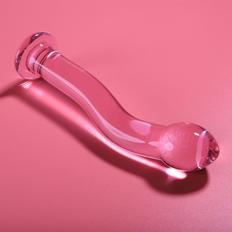 Gode en verre borosilicate rose couche sur fond corail, forme courbee a tete bulbe et base spherique brillante, sextoy lisse non poreux a sensations thermiques.