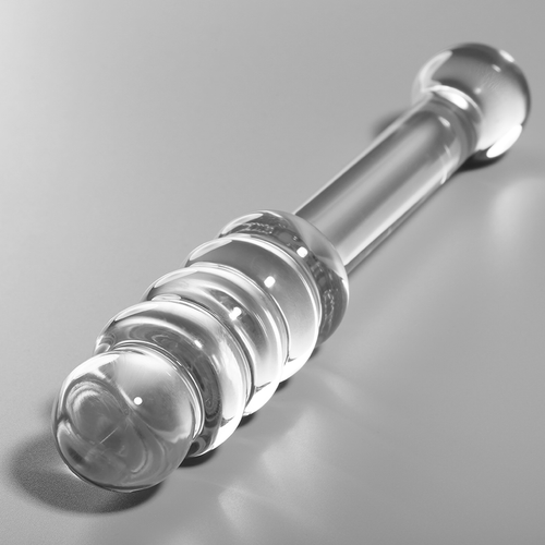 Gode en verre borosilicate transparent couche sur fond gris, serie de renflements anneles lisses et embout spherique, matiere non poreuse thermique.