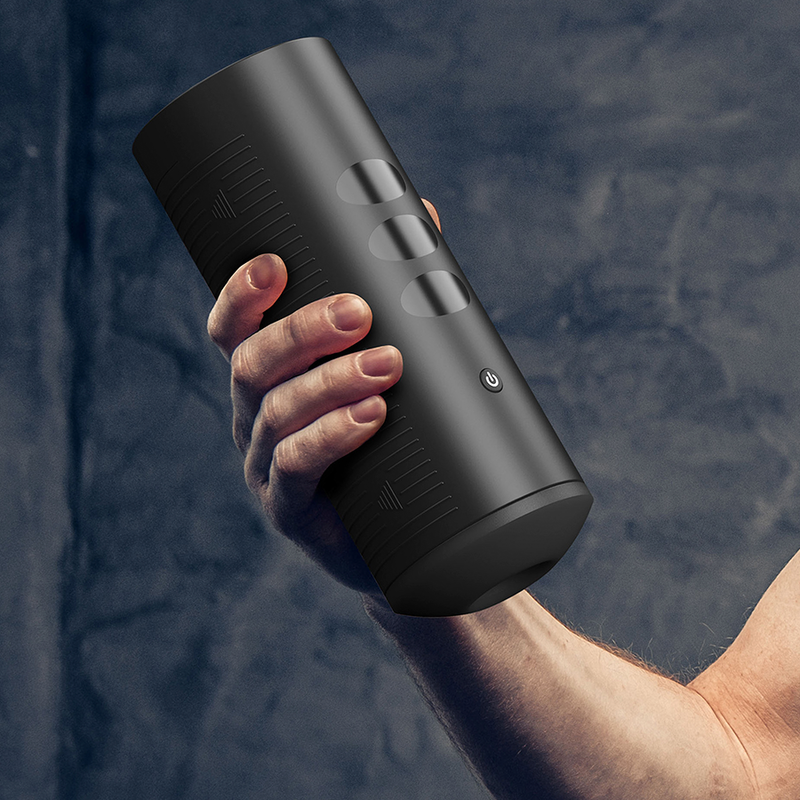 Masturbateur Titan tenu en main sur fond sombre, coque noire ergonomique a boutons tactiles, stroker vibrant interactif a neuf billes pilotable par telecommande et appli.