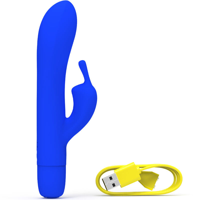 Vibromasseur rabbit bleu roi à oreilles externes et tige courbée à gauche, câble de charge jaune à droite. Double moteur en silicone, surface lisse satinée, coloris vif.