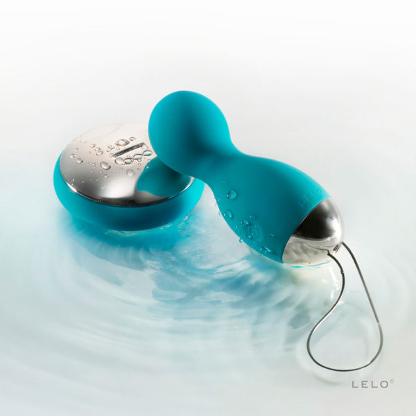 Œuf vibrant Lyla 2 bleu canard et sa télécommande posés à la surface de l'eau, illustration de l'étanchéité de ces sphères en silicone pilotables à distance.