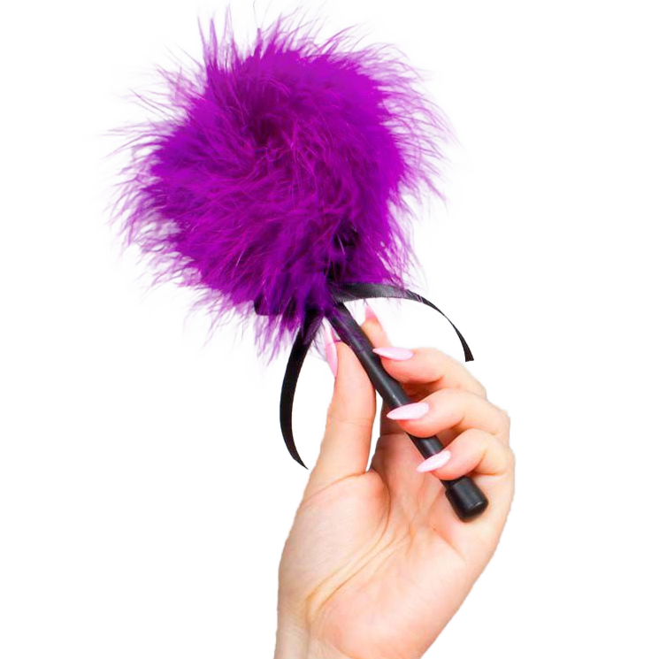 Plumeau tickler Secret Play en plumes violettes douces tenu en main par le manche noir, accessoire de caresse sensorielle pour jeux de domination douce et eveil de la peau.